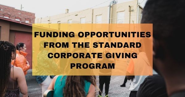 Image of group talking in an urban alleyway with text that says "Funding opportunities from the Standard corporate giving program"